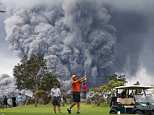 People watch at a golf course as an ash plume rises in the distance from the Kilauea volcano on Hawaii's Big Island as the USGS announces a major, explosive eruption is imminent